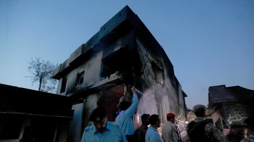 Army officers look around a badly damaged house