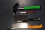 Kitchen knives, cleavers and a hammer are displayed next to a a ruler