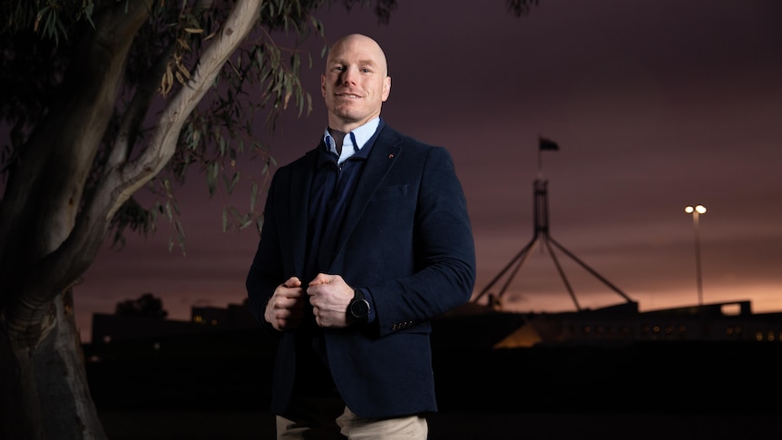 David Pocock looks out at distance in portrait taken in front of sunset at parliament house