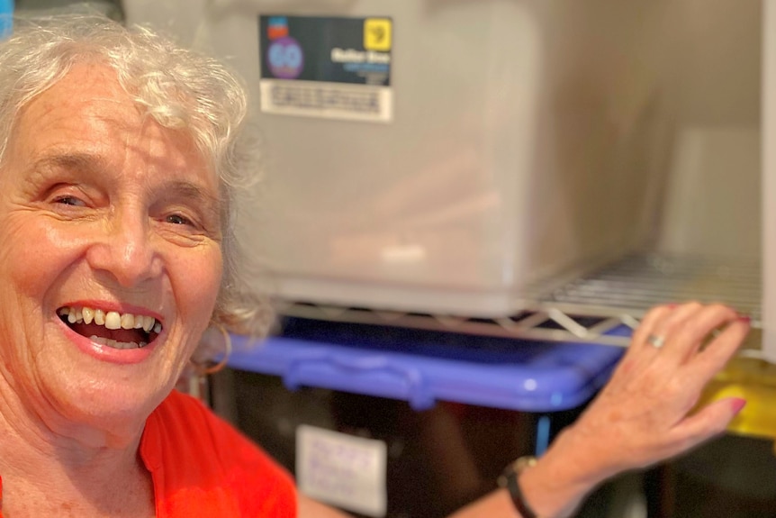 woman smiling holding on to a space on a shelf behind her