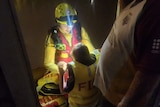 A child wearing a lifejacket standing in front of a swift water rescuer 