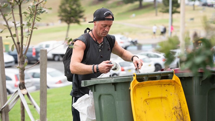 Dave Miller pulls out materials from a bin at Bondi beach.