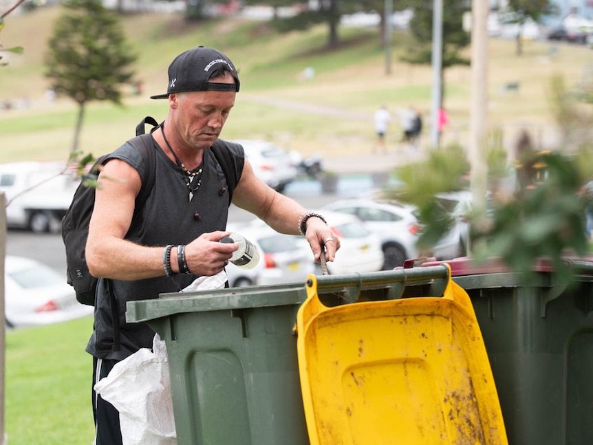 Dave Miller pulls out materials from a bin at Bondi beach.