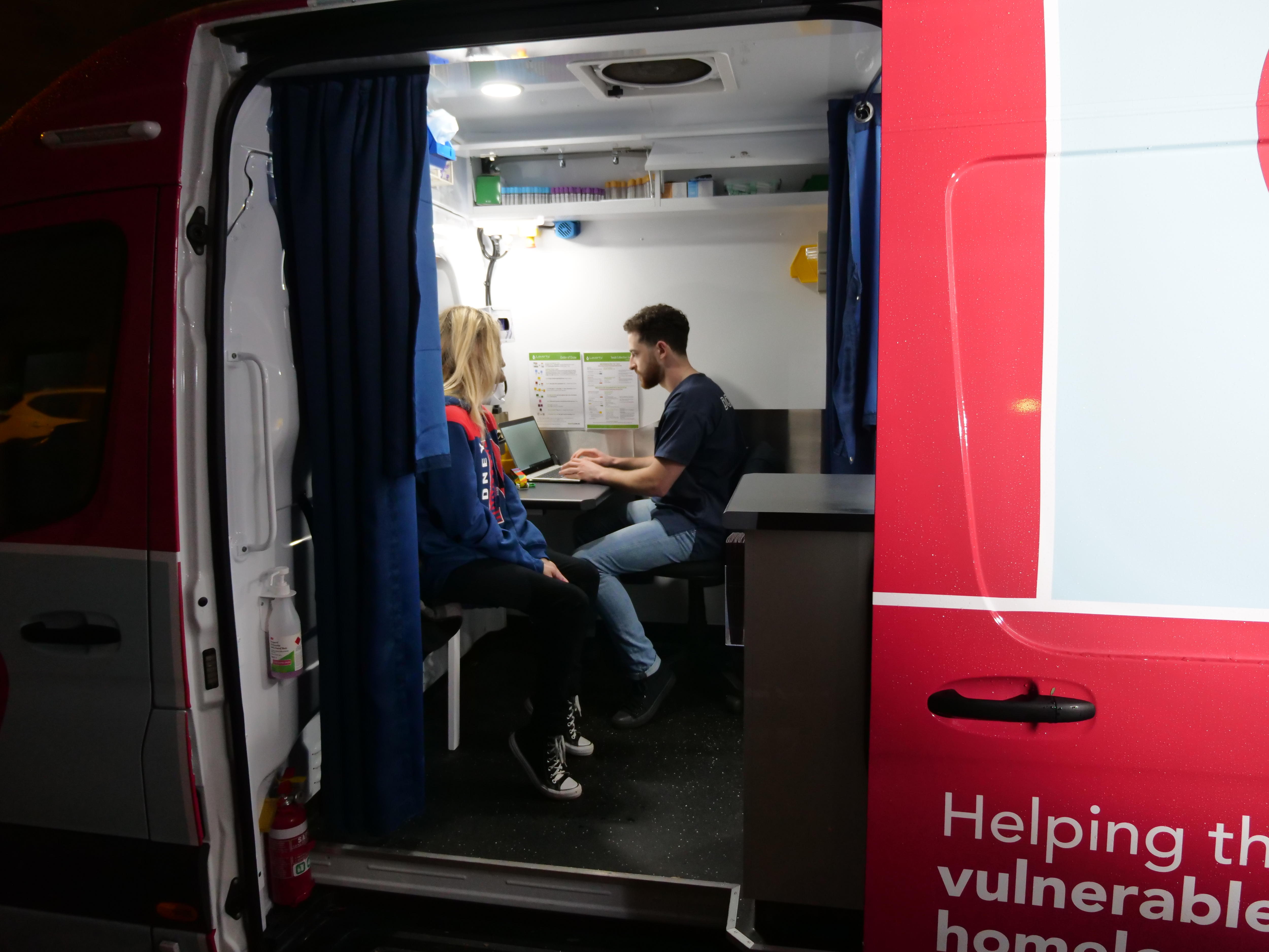 A woman and a man sit inside a van.