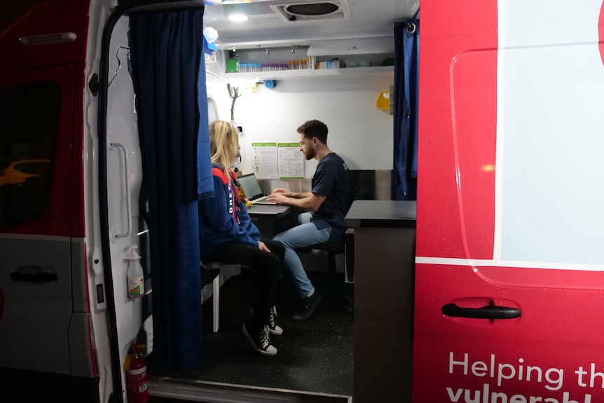 A woman and a man sit inside a van.