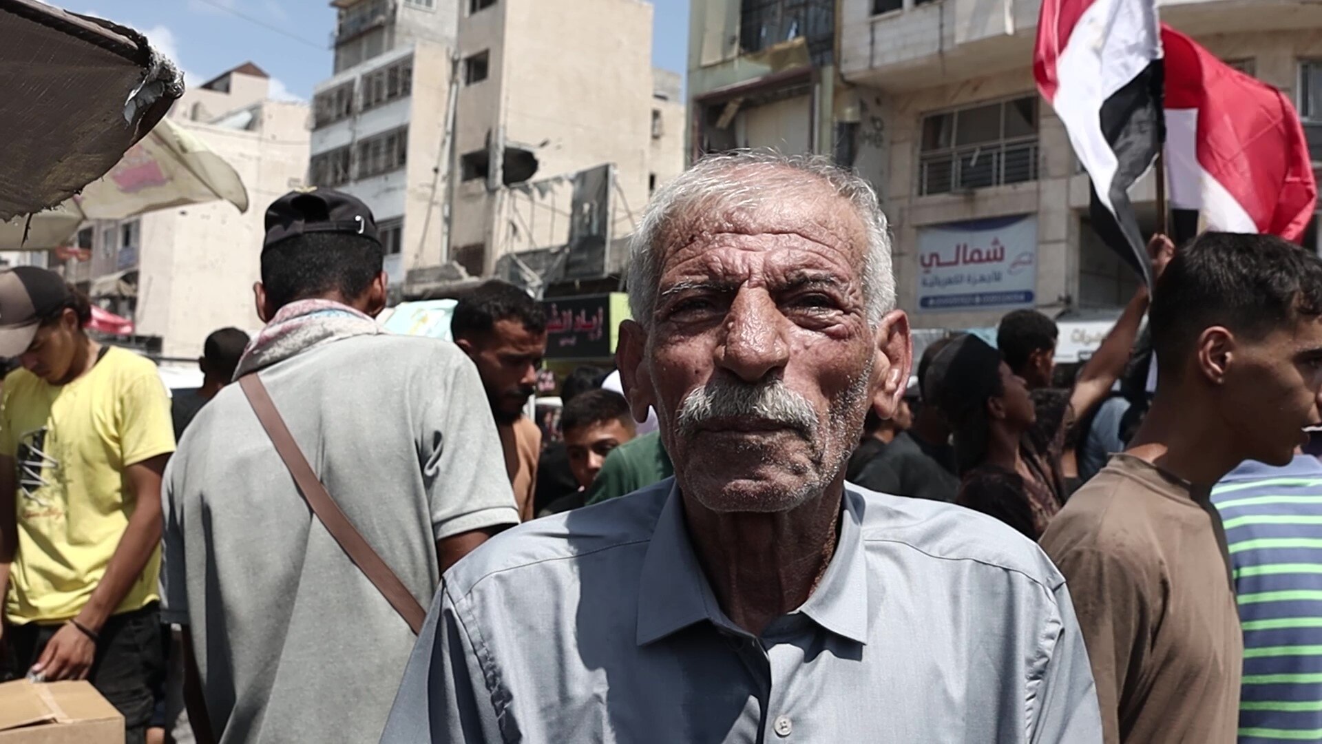 An old man, with thinning white hair and a white moustache, in bright sunshine.