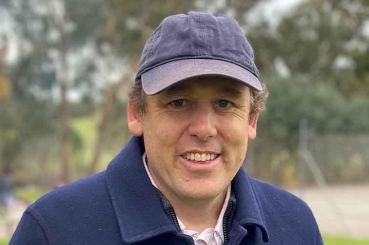 A man wearing a blue coat and blue baseball cap