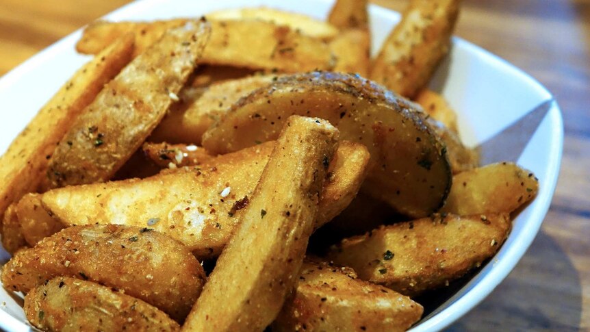 Seasoned potato wedges piled up in a white bowl.