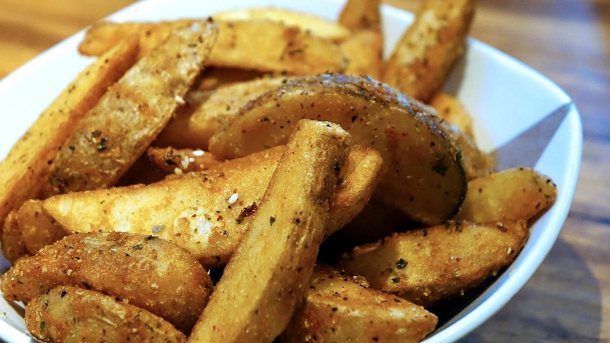 Seasoned potato wedges piled up in a white bowl.