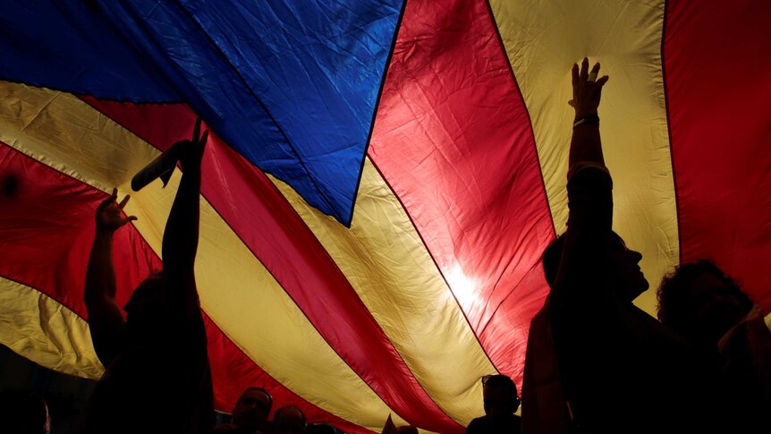 People hold up a giant Catalan separatist flag during a demonstration.