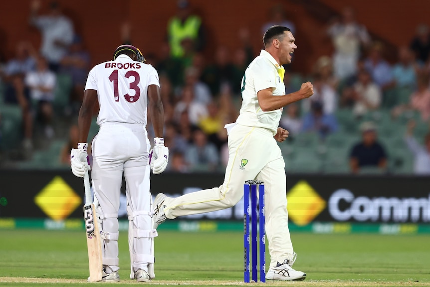 An Australian paceman runs down the pitch, passing a dejected West Indian batsman who has just got out.