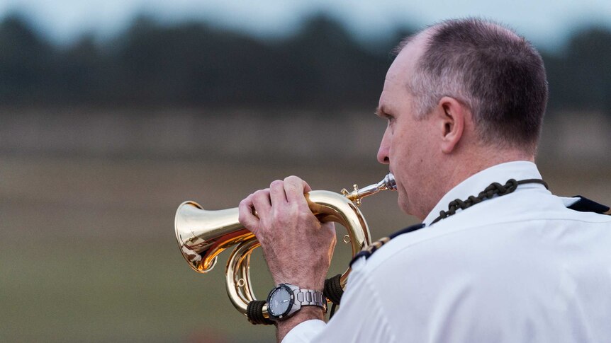 A man plays a bugle at an airport