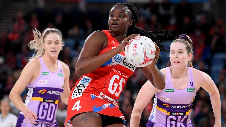 A NSW Swifts Super Netball player holds the ball in two hands against the Queensland Firebirds.