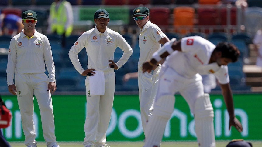 Australia fielders Marcus Harris, Usman Khawaja and Jhye Richardson watch Sri Lanka batsman Kusal Perera drop his helmet.