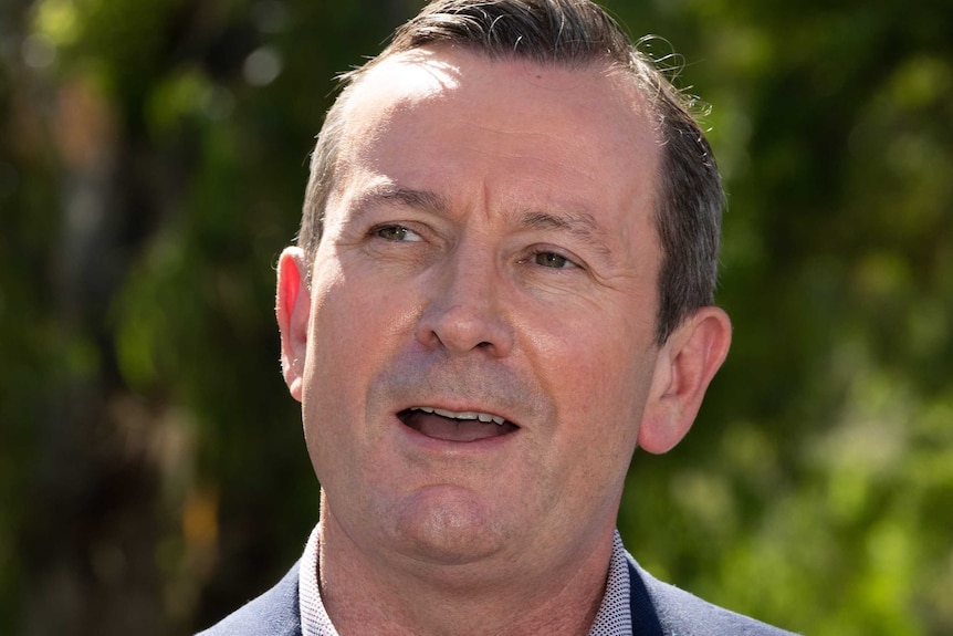 A close-up of WA Premier Mark McGowan at a press conference with trees in the background.