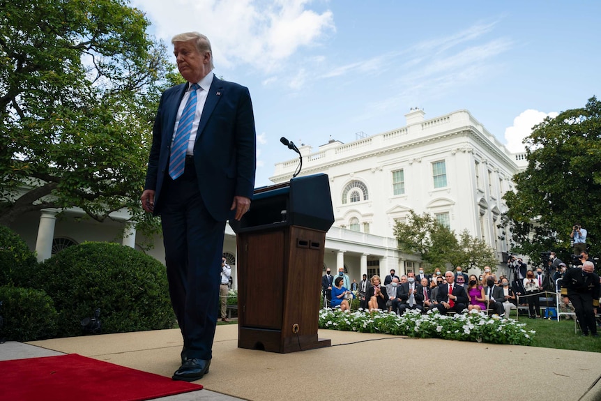 President Donald Trump is leaving a podium in the Rose Garden of the White House after a ceremony