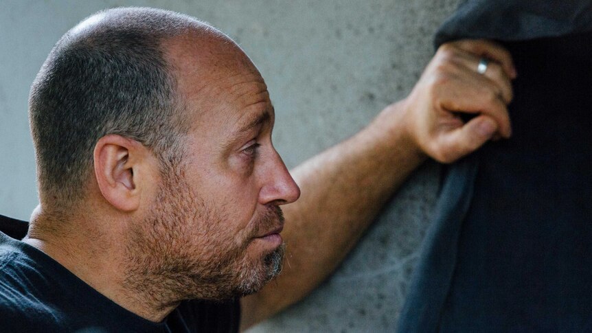 A man in a dark shirt looking into the distance.