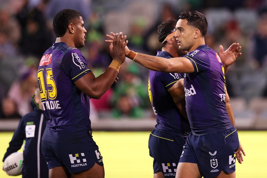 Melbourne Storm players Tui Kamikamica (left) and Reimis Smith high five during an NRL game.