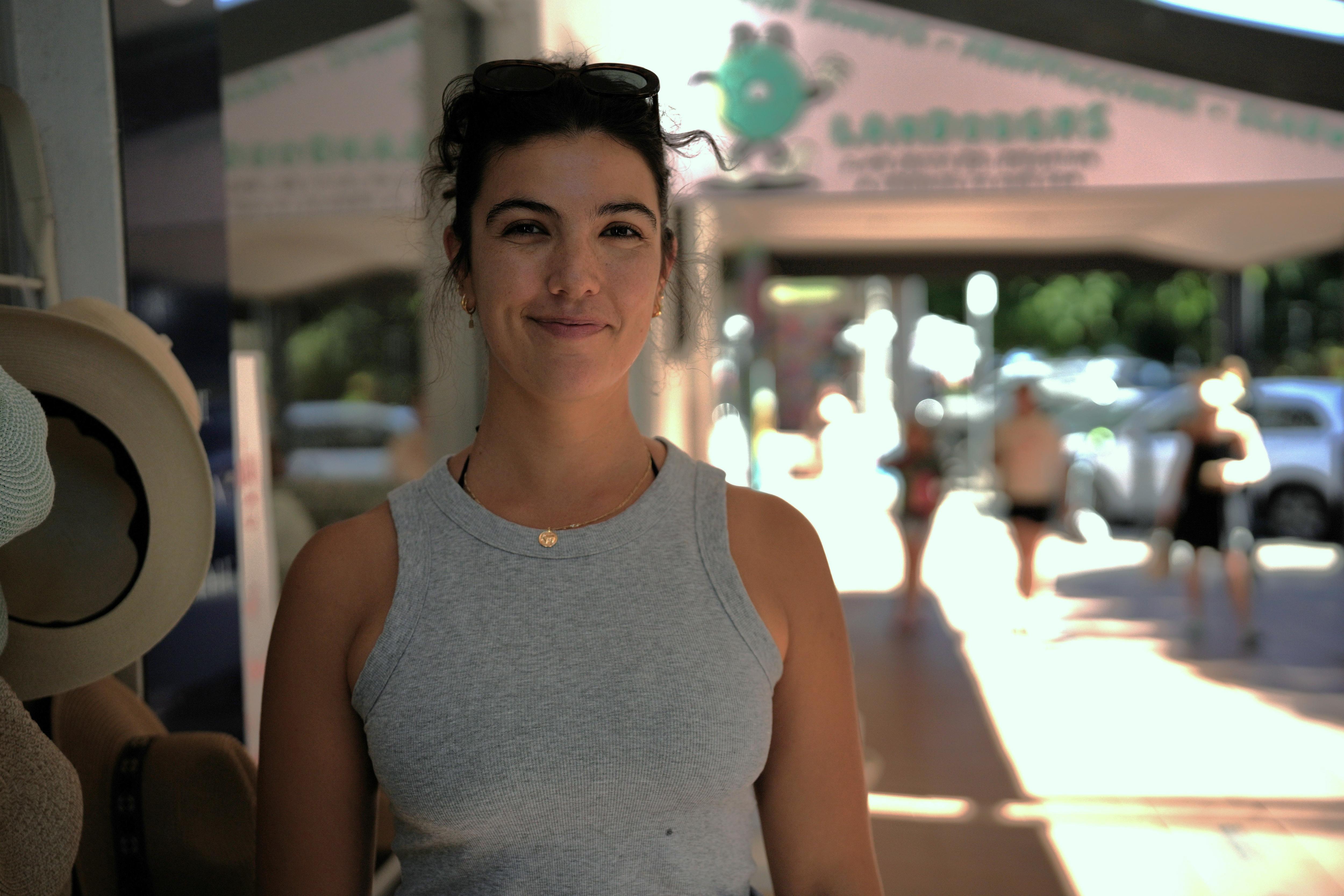 Una mujer joven sonriendo mientras está de pie a lo largo de un sendero suburbano.
