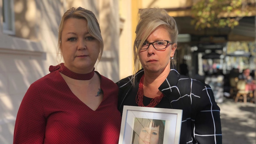 Michelle van Dyk and Sabine Kloss hold up a photo of Chrystal outside of court.