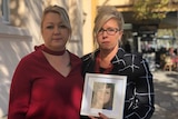Michelle van Dyk and Sabine Kloss hold up a photo of Chrystal outside of court.