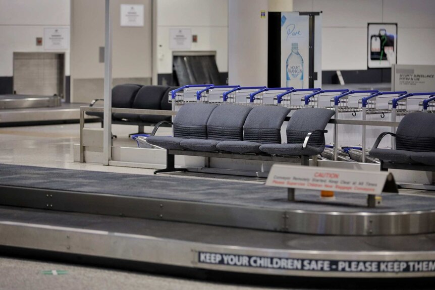 Empty chairs and luggage conveyer belt at an airport.