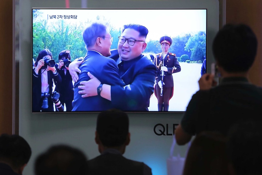 People watch a TV screen showing South Korean President Moon Jae-in, left, meets with North Korean leader Kim Jong Un