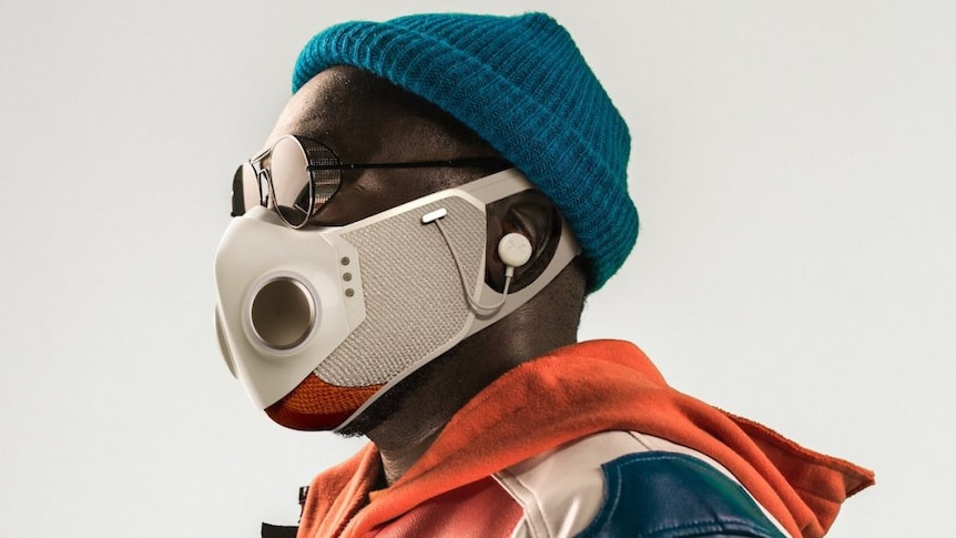 Image of rapper Will.I.Am wearing blue beanie, bespoke bluetooth face mask, orange and blue hoodie/jacket