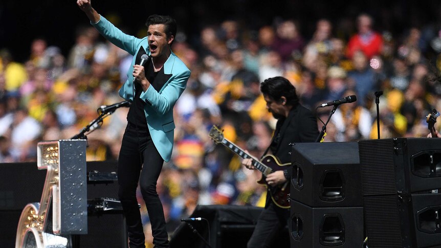 Brandon Flowers of The Killers gestures as he sings into a microphone at the AFL grand final.