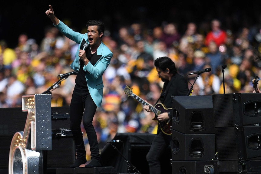 Brandon Flowers of The Killers gestures as he sings into a microphone at the AFL grand final.