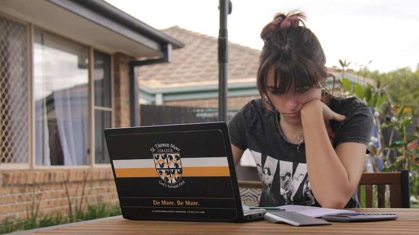 A teenager mopes at her laptop.