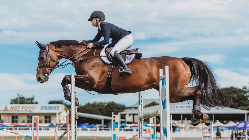A horse and rider jumping over a high jump