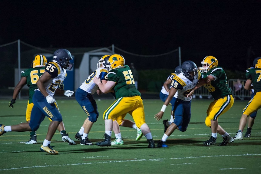 Eddie Sullivan is seen in green and yellow as he clashes against another player in blue and white, amidst a football game.