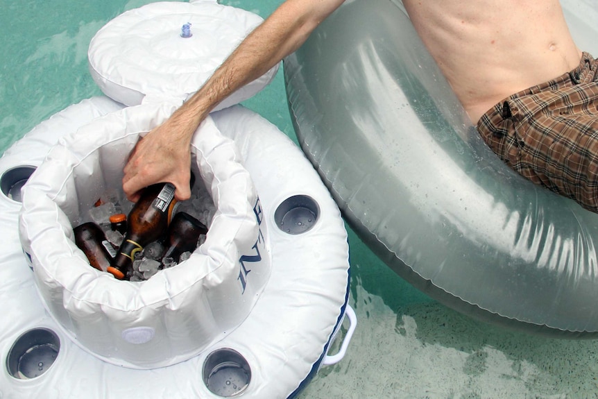 A man reaches into a floating pool esky.