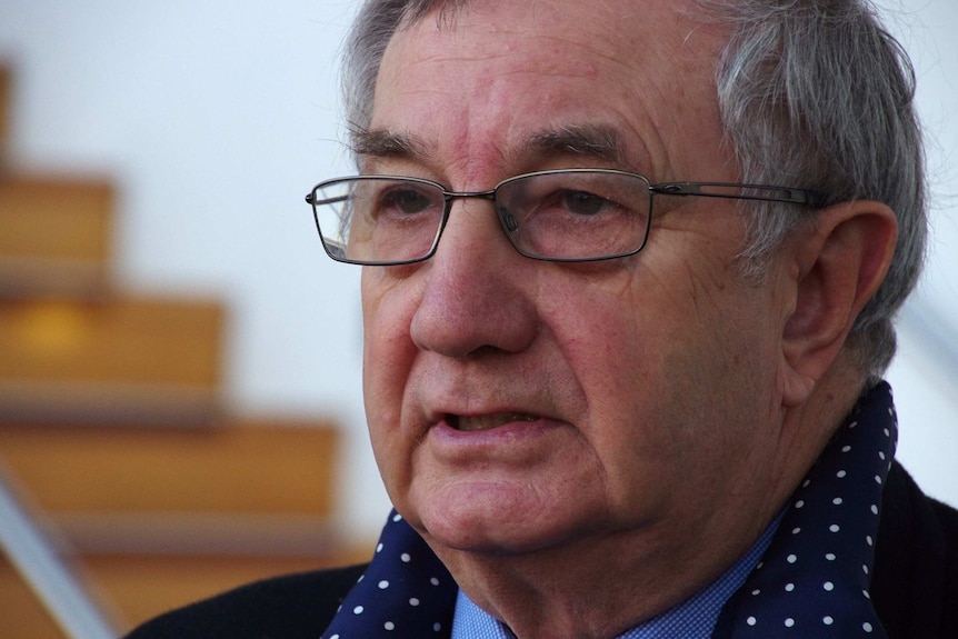 A tight head shot of John McKechnie with spectacles and a scarf on.