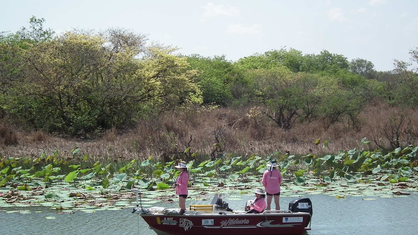 Three women fishing in a small boat on Corroboree Billabong.