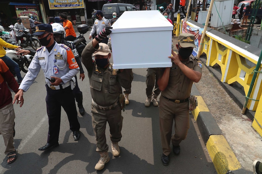 Indonesian officials carry a mock coffin as they walk around a busy intersection in Jakarta.