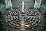 Federal parliamentarians stand, more than half of the seats in the house of representatives lay empty
