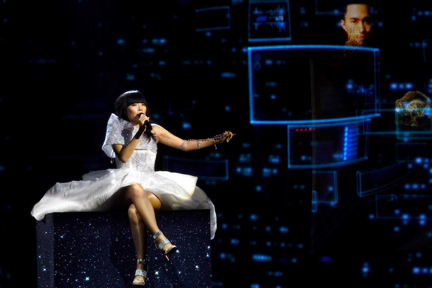 Dami Im sits on a raised platform and sings at Eurovision.