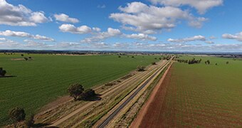 Bird's eye view of a rail line cutting through green fields