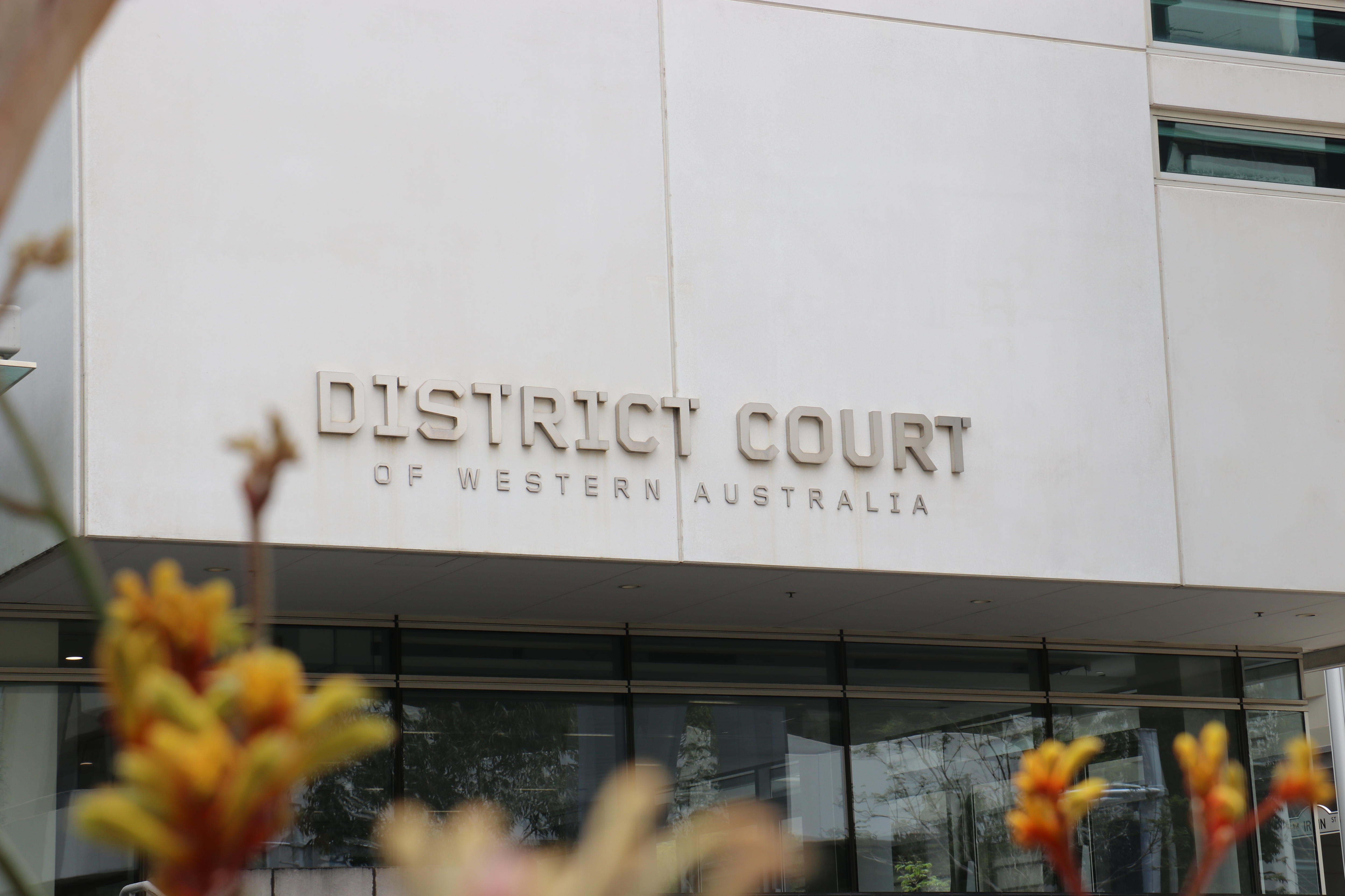 A light grey modern building with a sign that says District Court of Western Australia 