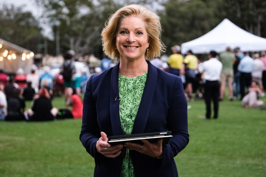 a woman tv journalist outdoors smiling and looking at the camera