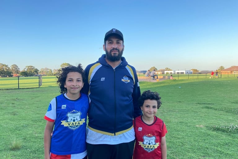 A man in sports gear with two young boys