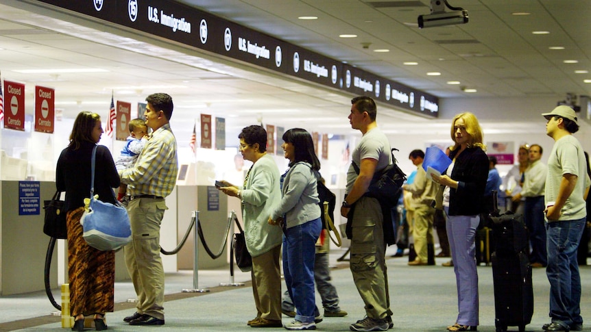 People wait in line at US Immigration at an airport.