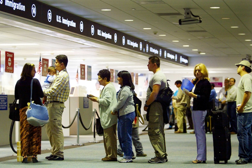 People wait in line at US Immigration at an airport.