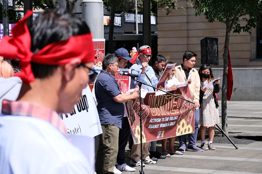 A person in red NLD bandana and other activists in background