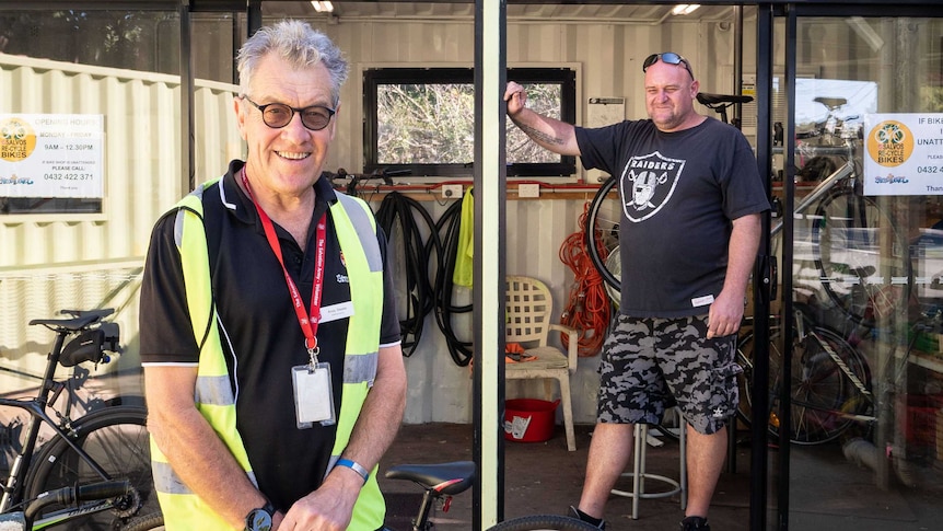 Andy Steele and Damien Saal pose outside a green shipping container that's been converted in a workshop.