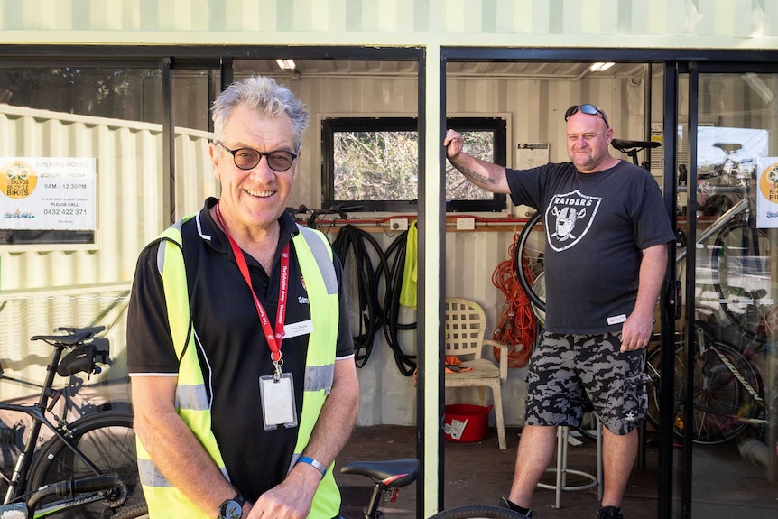 Andy Steele and Damien Saal pose outside a green shipping container that's been converted in a workshop.