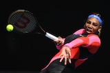 Serena Williams leans back, holds her left arm out in front of her and holds her racquet out at right angles to her body