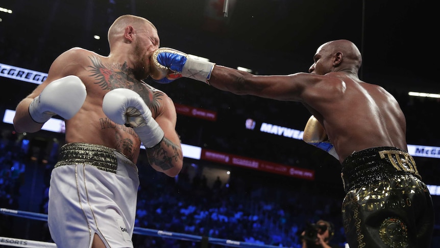 Floyd Mayweather punches Conor McGregor in the face.